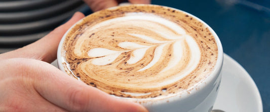 Barista serving a caramel latte with rosetta latte art