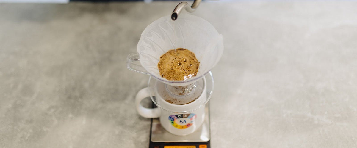 Pouring water over coffee in a V60 dripper on scales