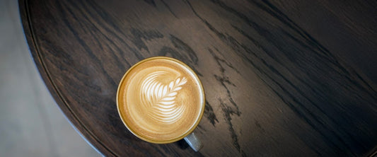 Small coffee with latte art on a dark wood table