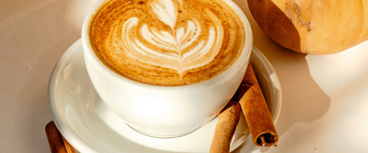 Pumpkin spice latte topped with cinnamon in an autumn setting