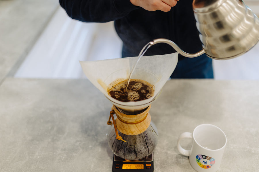 Pouring hot water over coffee grounds in a Chemex on brewing scales