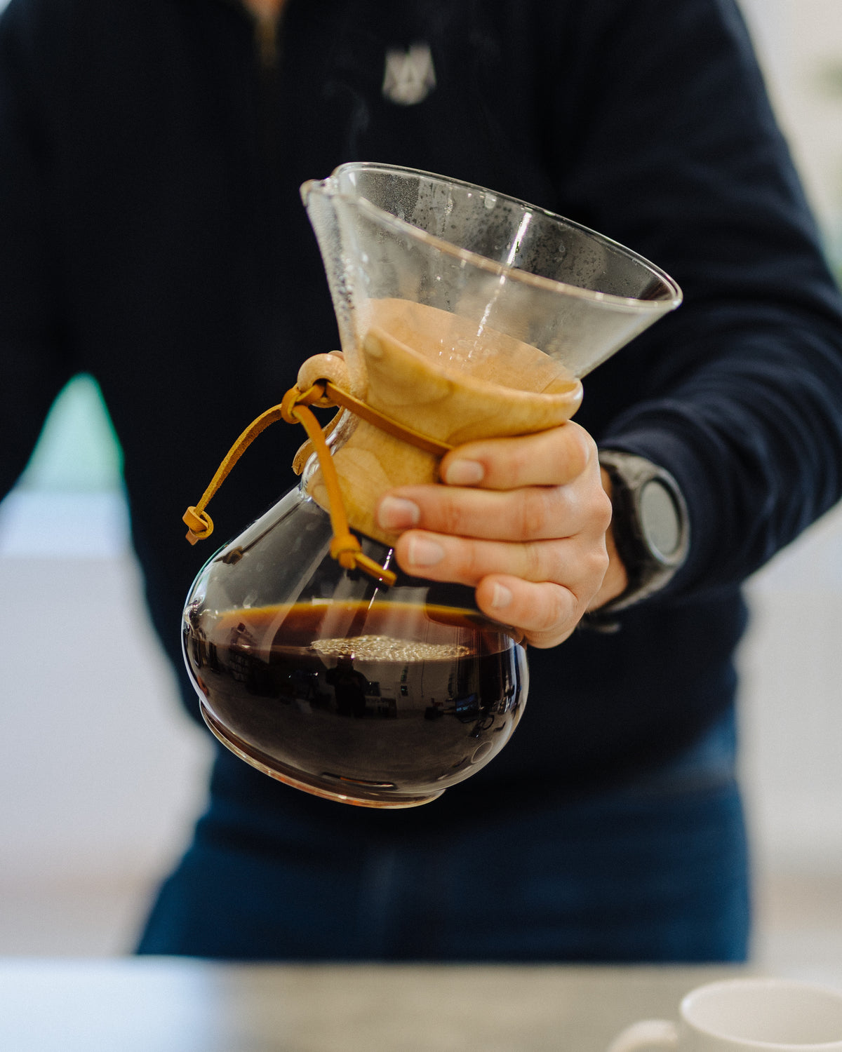 Holding a Chemex full of freshly brewed coffee