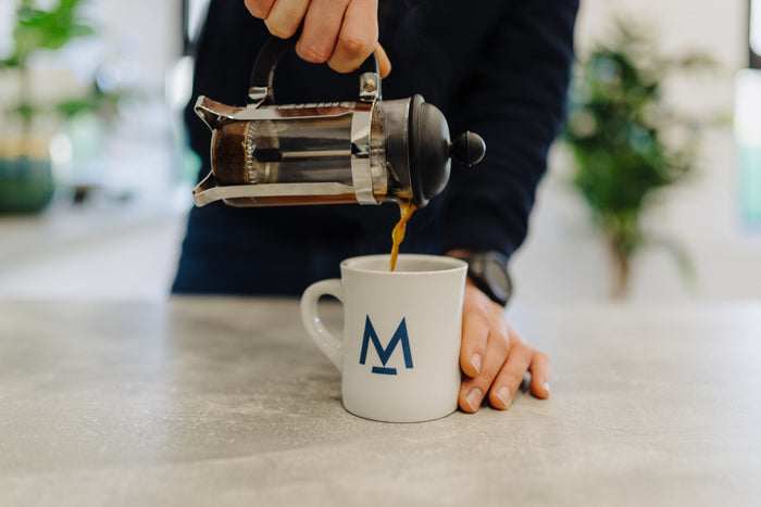 Pouring coffee from a cafetière into a mug
