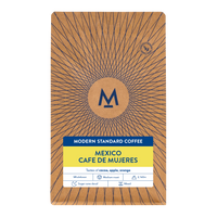 A package of Modern Standard Coffee's Mexico Cafe de Mujeres blend, featuring a brown kraft-paper style design with a blue sunburst pattern, a central circular logo, and a yellow and white label at the bottom.