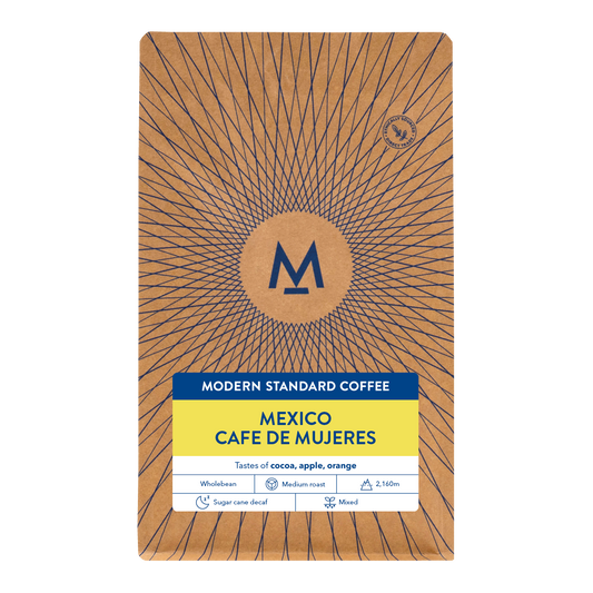A package of Modern Standard Coffee's Mexico Cafe de Mujeres blend, featuring a brown kraft-paper style design with a blue sunburst pattern, a central circular logo, and a yellow and white label at the bottom.
