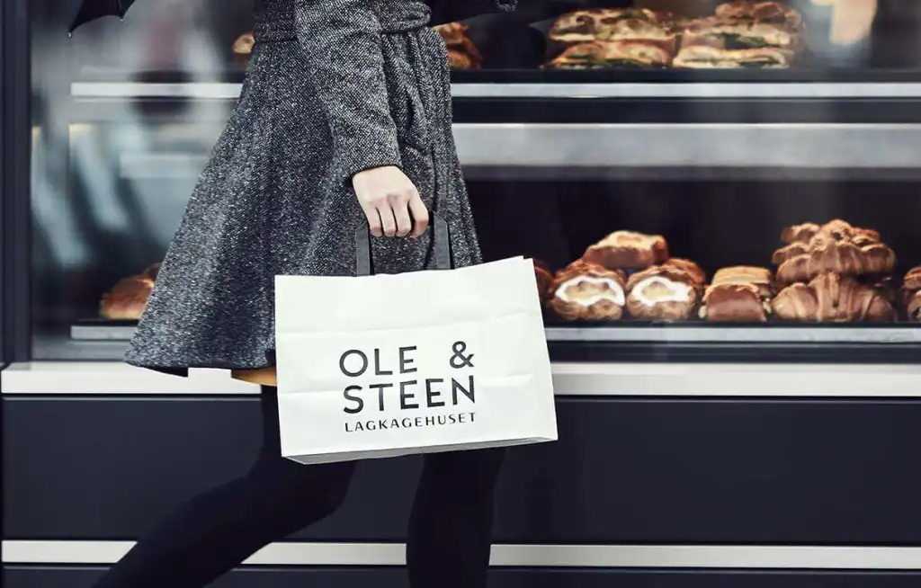 A customer carrying an Ole & Steen bag past the bakery counter