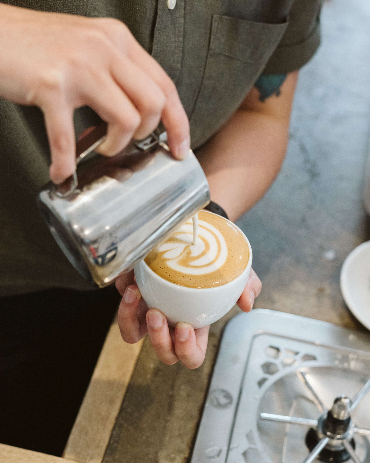 A barista pouring latte art into a cup